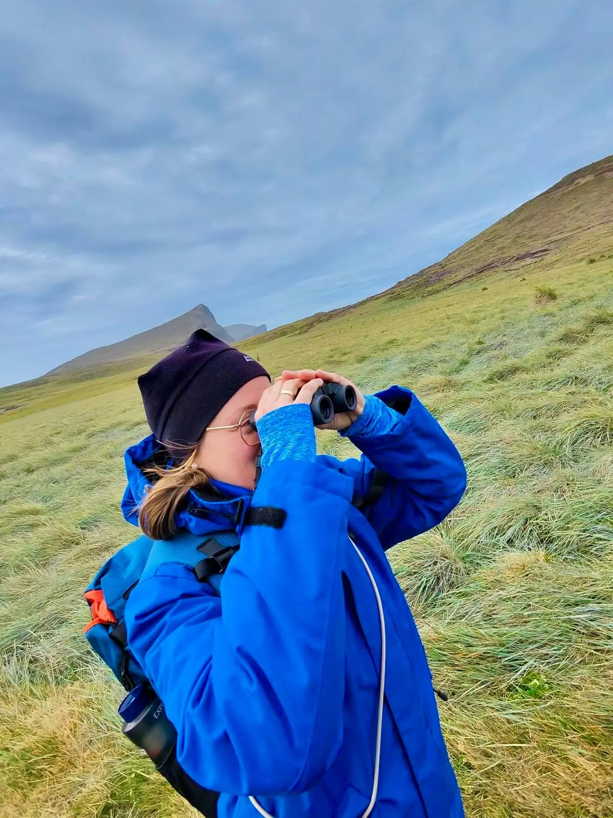 Mandy beobachtet mit einem Fernglas die Tierwelt der Falklandinseln