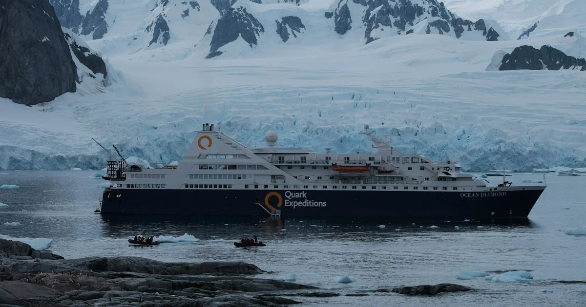 Expeditionsschiff vor schneebedeckten Bergen im Polarwasser