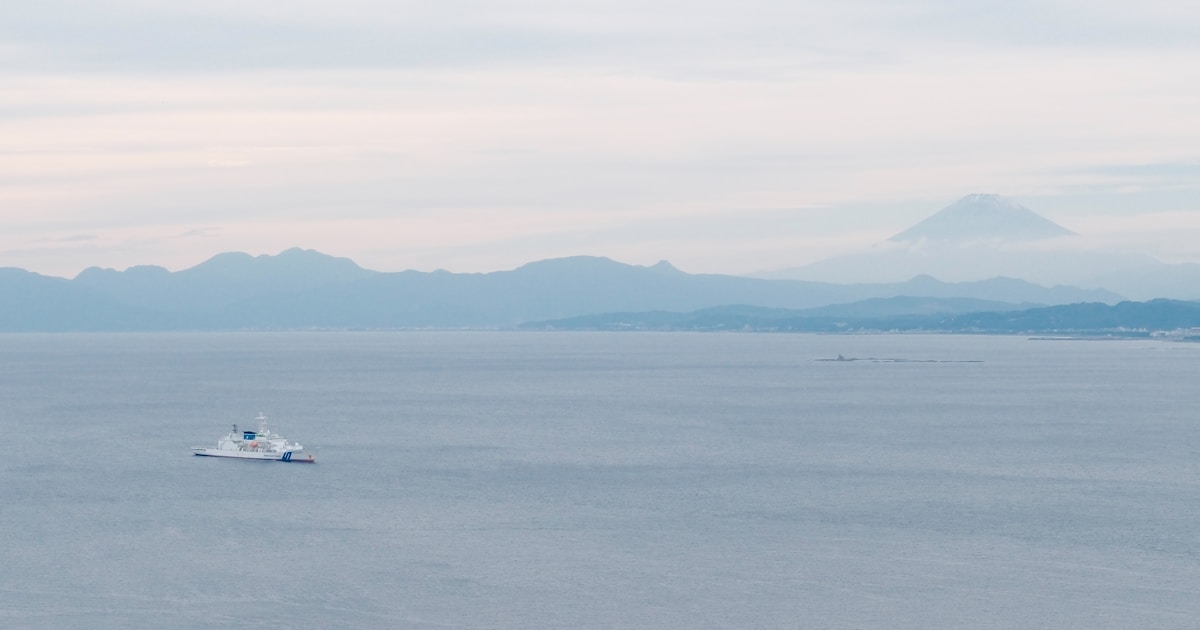 Blick über die Suruga-Bucht auf den Fuji, im Vordergrund ein Schiff vor der japanischen Küste