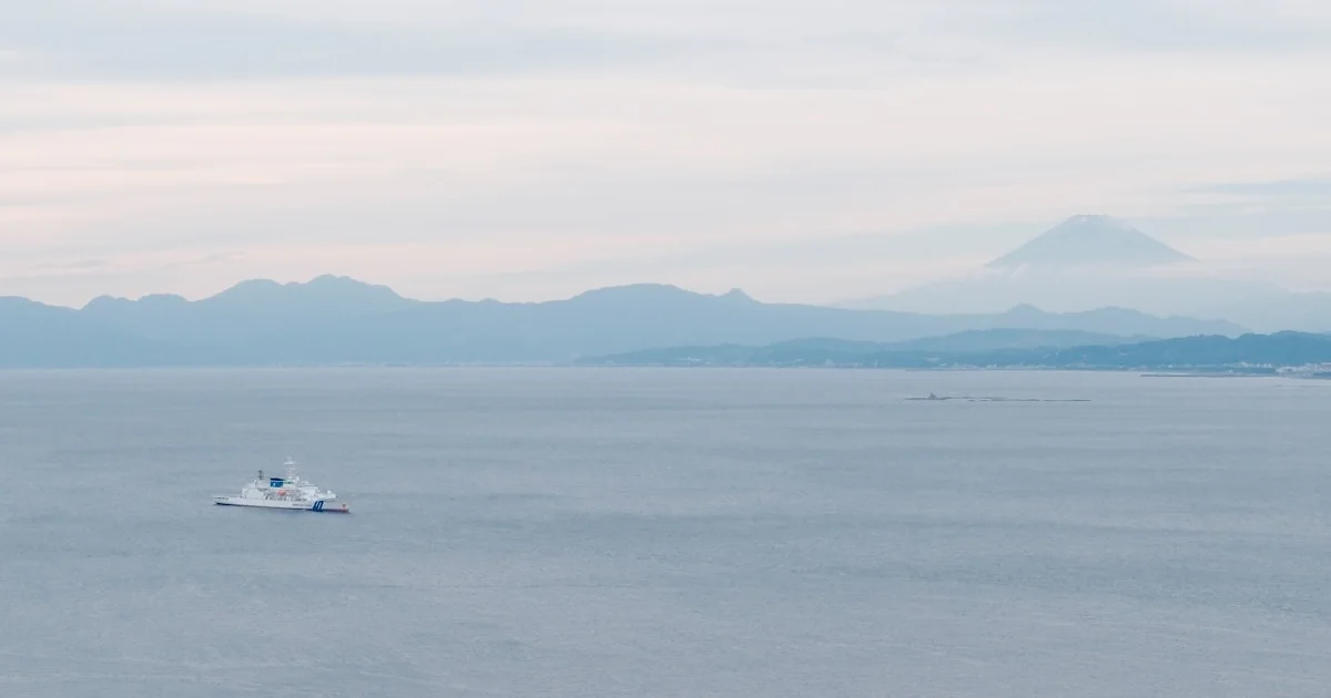 Blick über die Suruga-Bucht auf den Fuji, im Vordergrund ein Schiff vor der japanischen Küste