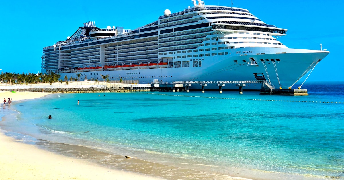 Karibik-Kreuzfahrt – Schiff vor türkisfarbenem Wasser und Palmenstrand