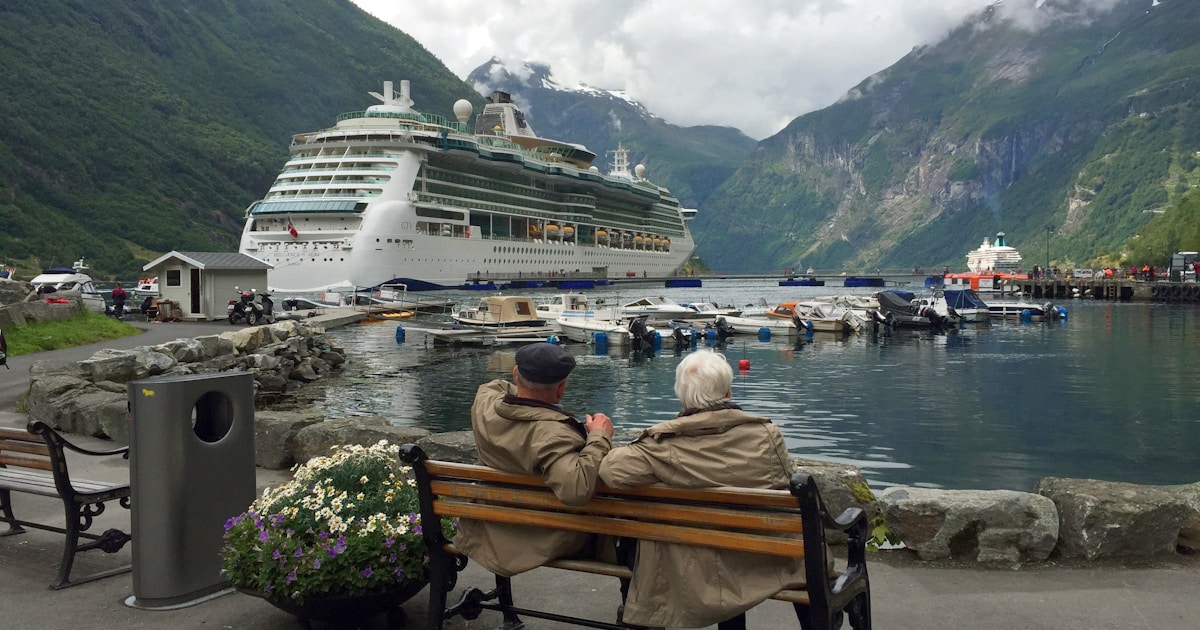 Reisendes Paar an der Reling eines Kreuzfahrtschiffs im norwegischen Geirangerfjord