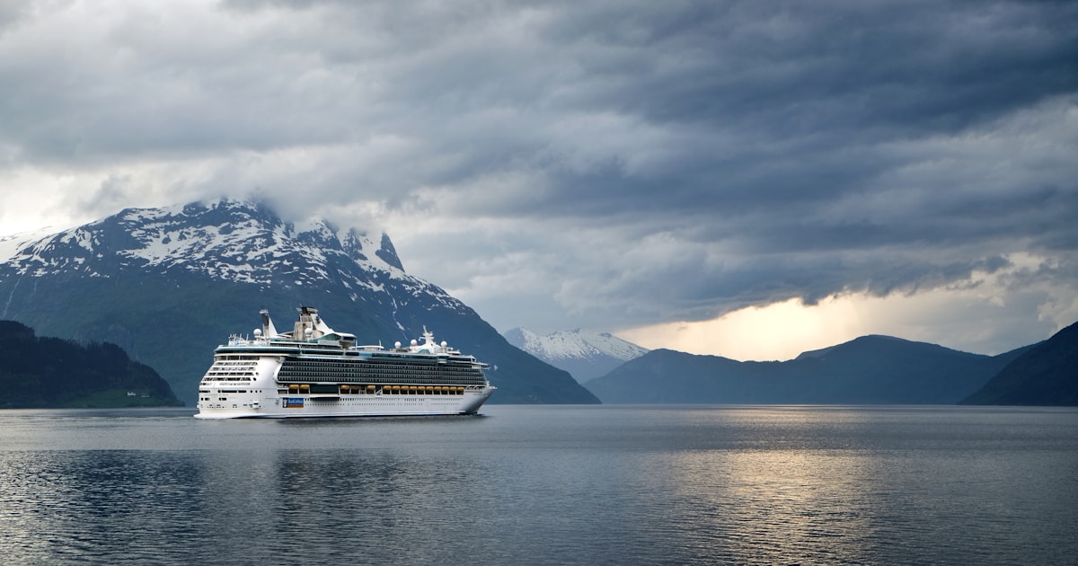 Kreuzfahrtschiff in einem norwegischen Fjord zwischen steilen Bergflanken – Sinnbild für nachhaltige Kreuzfahrt