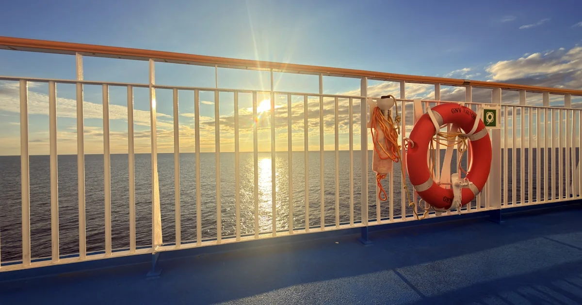 Alleinreisende Person an der Reling eines Kreuzfahrtschiffs mit Blick auf den Ozean