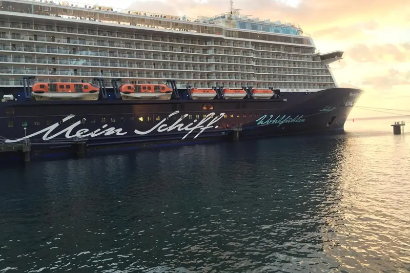 Mein Schiff 3 mit Schriftzug am Bug im Hafen, Abendlicht über dem Wasser