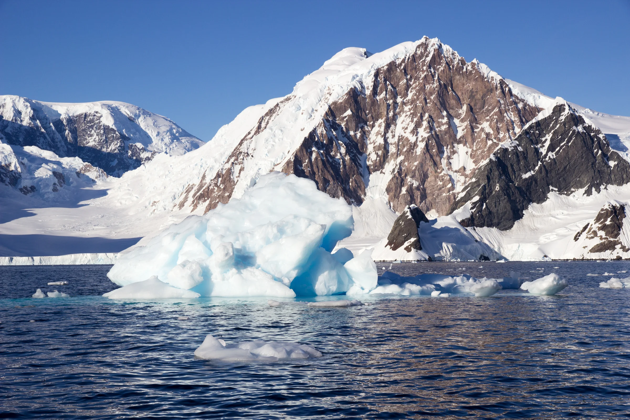Eisberge vor den verschneiten Bergen der Paradise Bay in der Antarktis